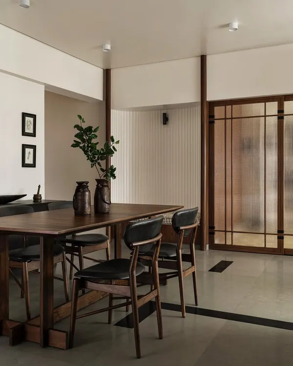 The dining area in Apartment 1005 features an assortment of custom hardwood pieces, including a sturdy dining table and chairs. The space is defined by a unique 'Tetris' floor pattern using grey Kota stone and black granite inlays.