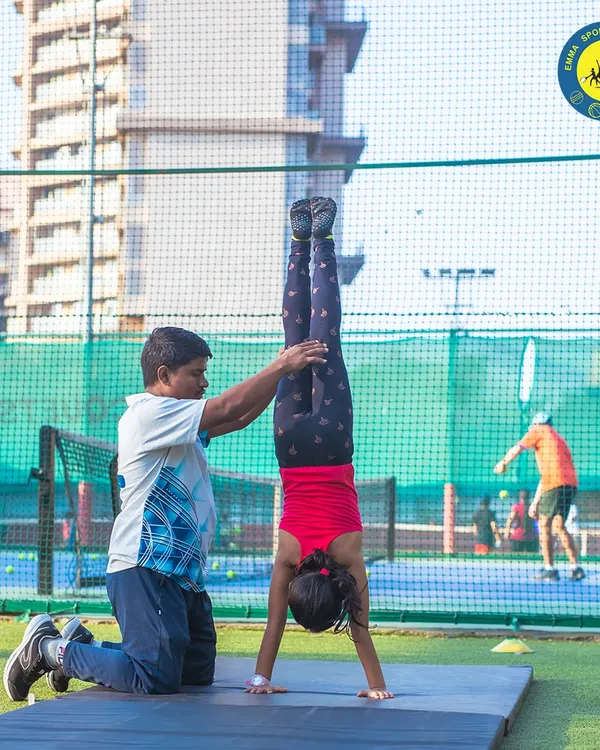 One of our junior gymnasts masters a handstand with the help of a coach. I ensure every child receives the support they need to build strength and fearlessness.