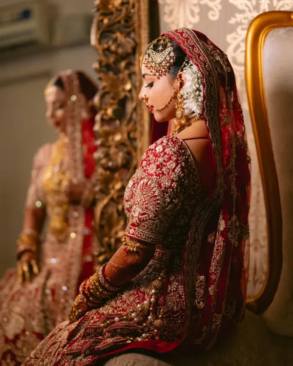 Veiled in enduring majesty, this bride shines in eternal red. This close-up highlights the intricate handwork on the blouse and the traditional jewelry that completes the Nikah look.