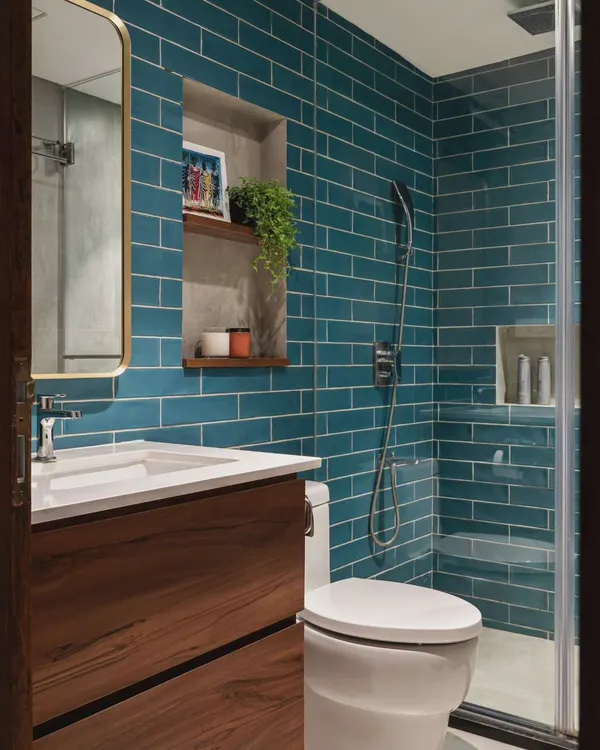 This bathroom shows how a simple switch of tile color can transform a space. The vibrant teal subway tiles create a fresh and energetic vibe, beautifully complemented by the warm wood vanity and brass mirror frame.