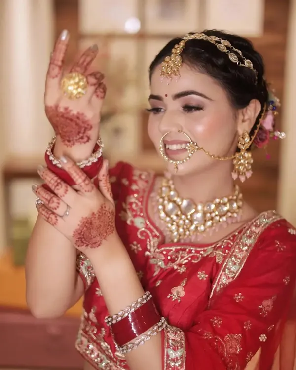 A beautiful, smiling bridal portrait capturing the bride's happiness and intricate details, from her mehendi to her stunning jewelry.