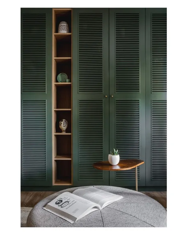 This custom-built wardrobe in a bold teal green acts as a statement piece in the home theater. The louvered doors add texture, while the open wooden niche breaks up the color and provides a space for display.