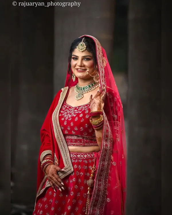 A radiant bride in a classic red lehenga, her happy expression perfectly captured. This portrait showcases my skill in using soft lighting to create a flattering and celebratory image.