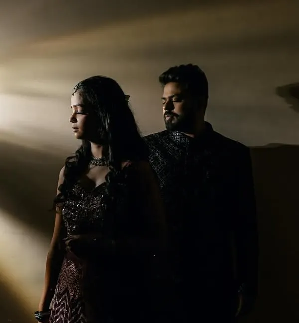 A stunning portrait using projected light to create dramatic rays. The couple stands in the shadows, creating a moody and cinematic feel perfect for an engagement or sangeet shoot.