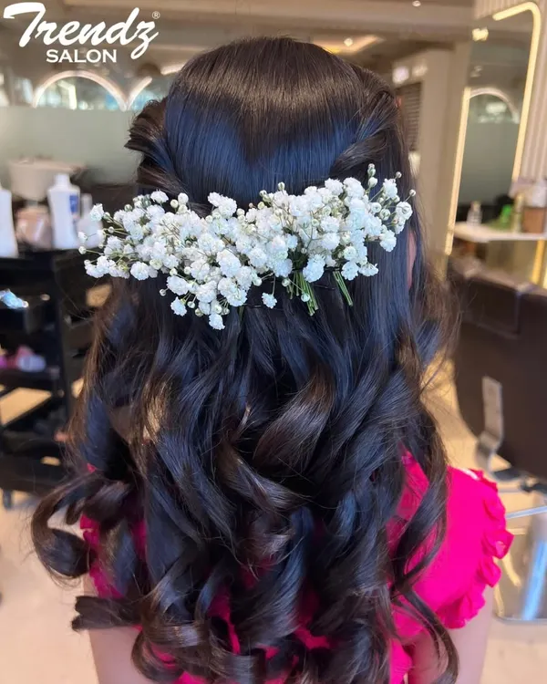 A romantic half-up, half-down hairstyle perfect for any special occasion. The soft curls are adorned with delicate baby's breath, adding a touch of natural elegance.