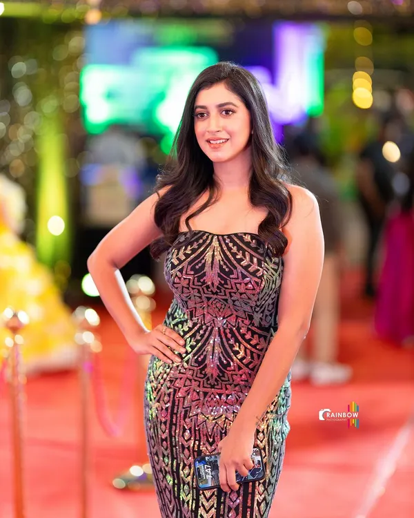 A classic red carpet shot. The model's confident pose and the shimmering gown are perfectly captured against the backdrop of event lighting, creating a glamorous and exciting photo.