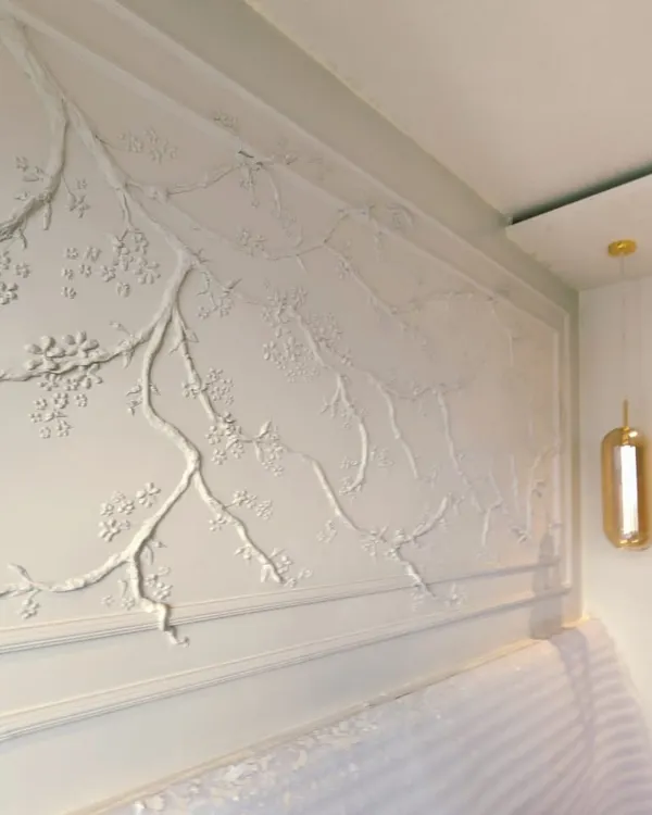 The finished cherry blossom mural, created for a young student's bedroom. The monochromatic, textured branches and blossoms create a subtle yet impactful statement, transforming the wall into a serene sanctuary that celebrates nature.