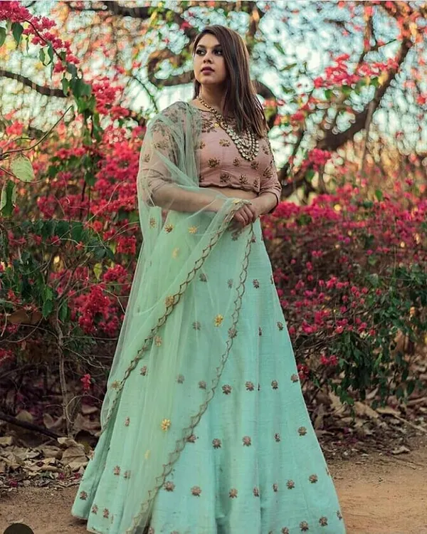 A model in a beautiful mint green lehenga with a contrasting pink blouse. The delicate embroidery makes this a fresh and elegant choice for a daytime wedding function or a sangeet.