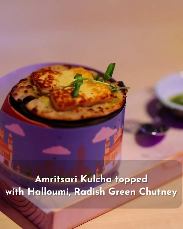 A modern interpretation of a Punjabi classic. This Amritsari Kulcha is topped with grilled halloumi cheese and served with a side of radish green chutney, all presented in a stylish, custom-branded container.
