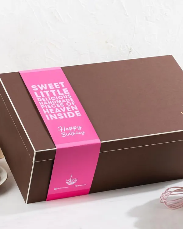 Taking gifting to the next level with our signature gift hampers. This large, elegant brown box is sealed with a custom "Happy Birthday" sleeve, promising "sweet little delicious handmade pieces of heaven inside".