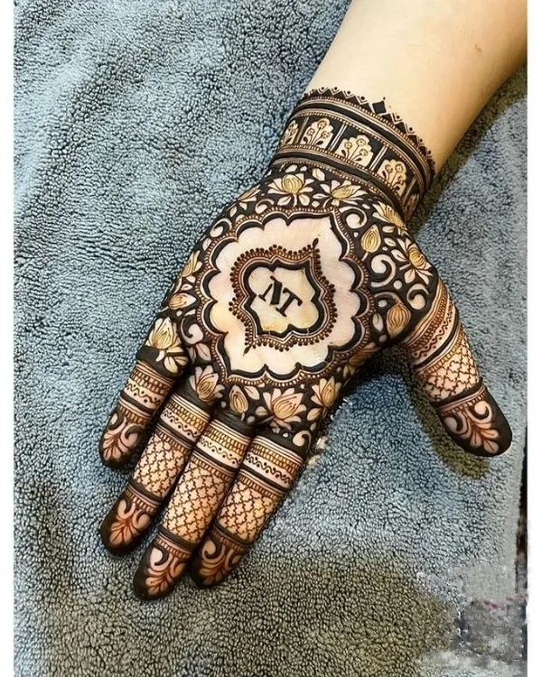 A beautiful way to personalize your mehndi. This design features the couple's initials 'NT' in a stylish font at the center of the palm, surrounded by a floral mandala.