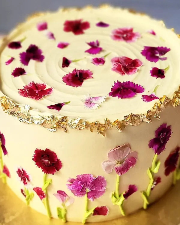 Sometimes less is more. This elegant cake is decorated with pressed edible flowers and a touch of gold leaf for a simple, natural beauty.