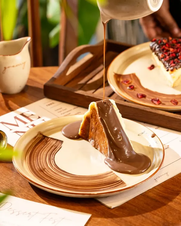A river of warm chocolate sauce being poured over a San Sebastian cheesecake. This shot is pure indulgence and designed to trigger cravings.