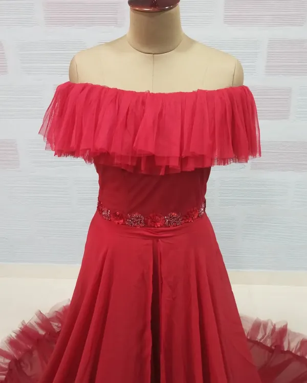 A close-up of our red off-the-shoulder gown, featuring a ruffled tulle neckline and an embellished waistband. This style is a fantastic rental option for maternity shoots or pre-wedding photos.