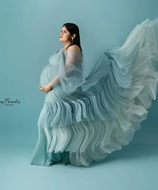 The movement of this ethereal blue gown by the window creates a breathtaking silhouette, capturing a moment of quiet contemplation and grace.