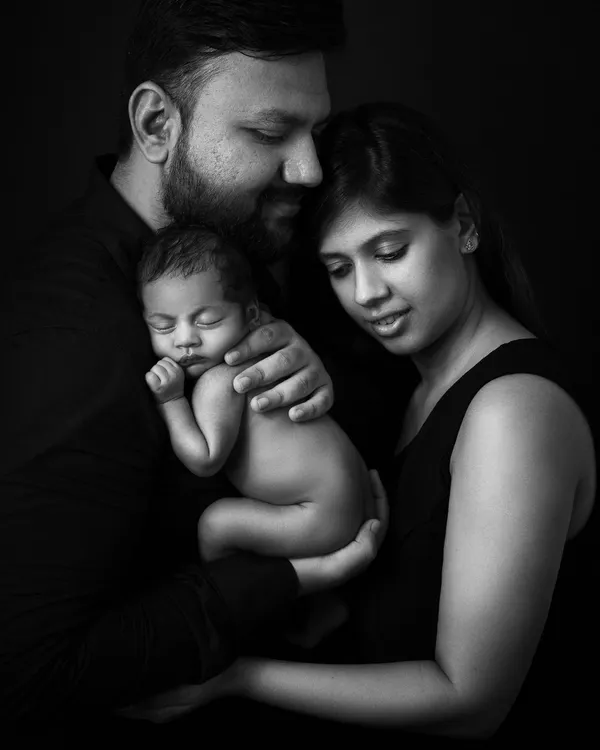 A family's love, captured in dramatic low-key lighting. Black and white photography strips away everything but the emotion, creating a powerful and eternal memory.