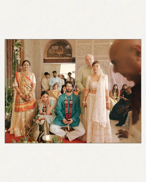 A temple wedding, captured with a documentary feel. This wide shot shows the couple amidst their family during the ceremony, giving a sense of the sacred space and the community witnessing their union. The perspective from behind a priest adds a layer of authenticity.