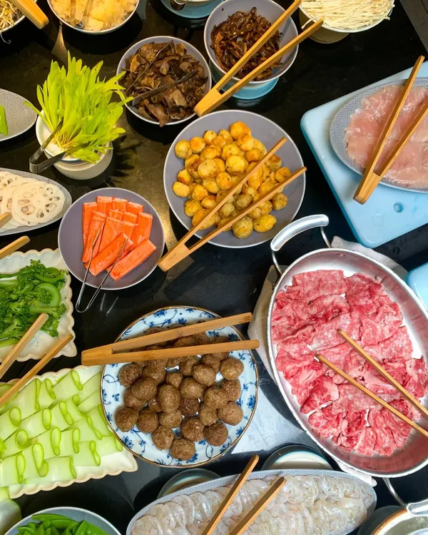An abundant spread of fresh ingredients for our interactive hot-pot station. Guests can choose from thinly sliced meats, seafood, meatballs, and a variety of crisp vegetables to cook in their simmering broth.