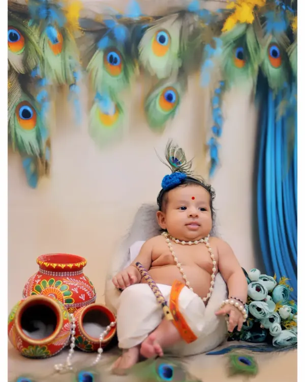 A full portrait of a baby dressed as Little Krishna, seated with pearl necklaces and decorative matkas against a backdrop of peacock feathers. This is a classic pose for my Janmashtami themed shoots.