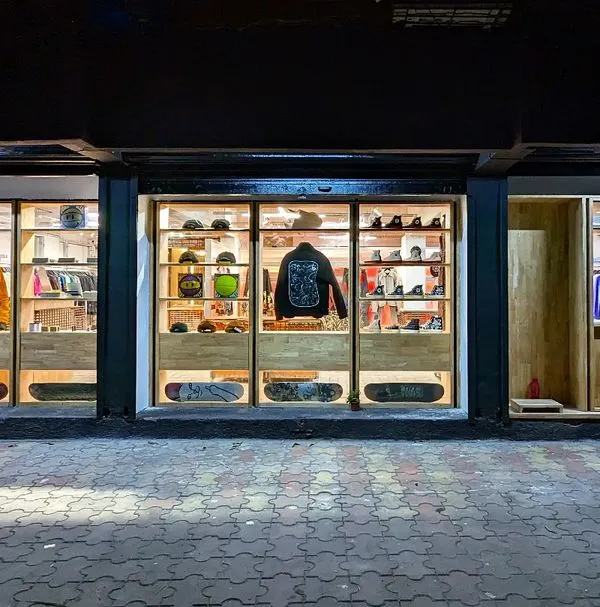 The completed facade of Capsul at night, fully illuminated. The design creates a series of glowing vitrines, turning the storefront into a beacon in the neighborhood and showcasing the products within like gallery pieces.