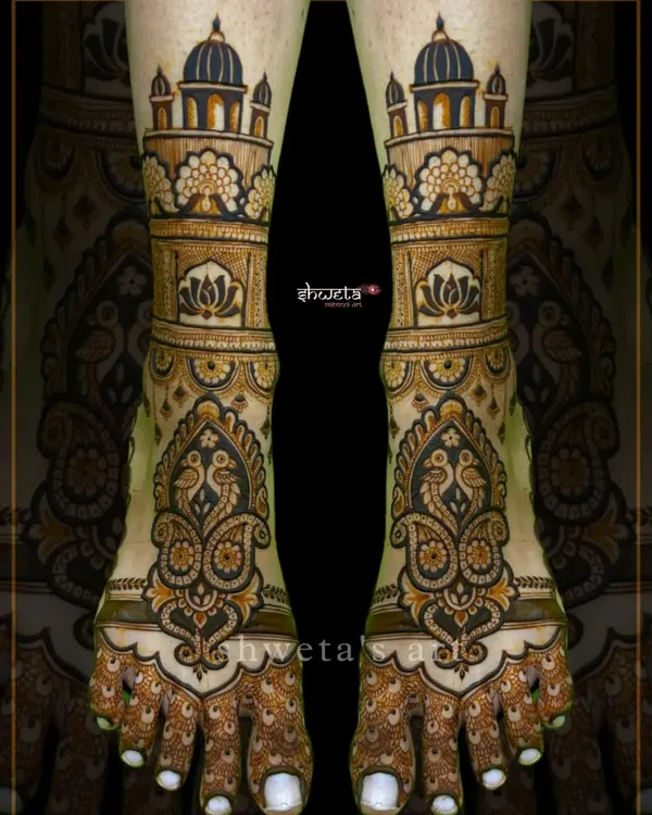 A regal leg mehendi design featuring architectural domes and intricate paisley peacock motifs. This pattern creates a stunningly symmetrical and grand look for the bride's feet.