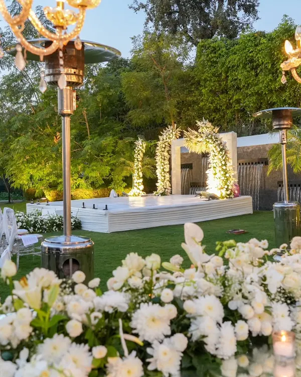 A breathtaking view of an all-white 25th-anniversary celebration. The setup features a pristine white stage, elegant seating, and lush floral arrangements, creating a picture of pure sophistication.