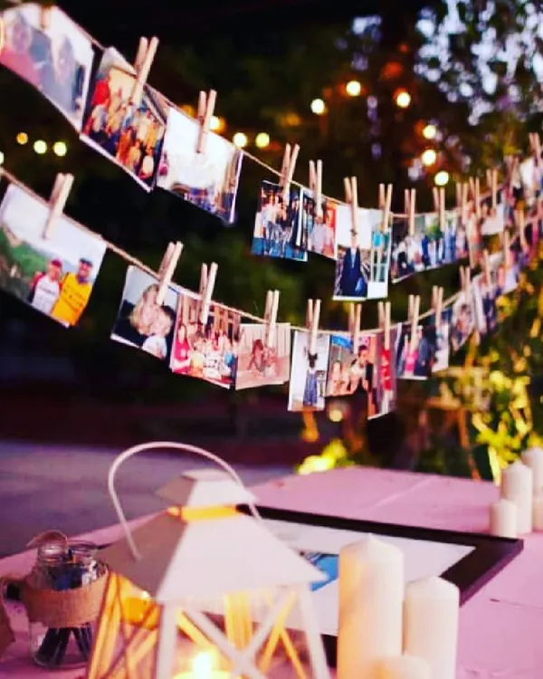 A rustic and charming way to display your memories. I create a photo garland using twine and wooden clothespins, perfect for an outdoor or indoor setting, illuminated by candles and string lights for a warm evening glow.
