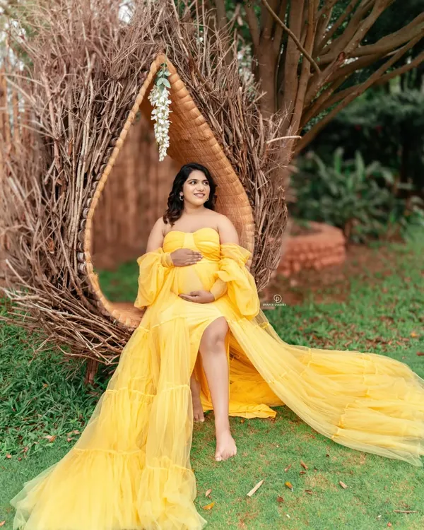 A radiant mom-to-be enjoying a beautiful day outdoors. This nest-like chair and the vibrant yellow gown create a stunning, bohemian-inspired look for a garden maternity shoot.