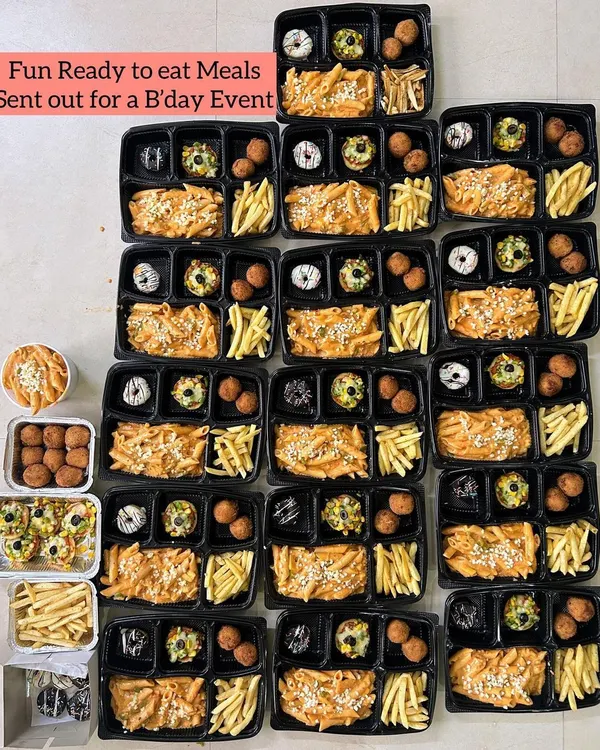 A colorful and abundant display of fun, ready-to-eat meal boxes prepared for a birthday event. Each box is filled with kid-friendly favorites like pasta, fries, and doughnuts, showcasing my ability to cater for children's parties.