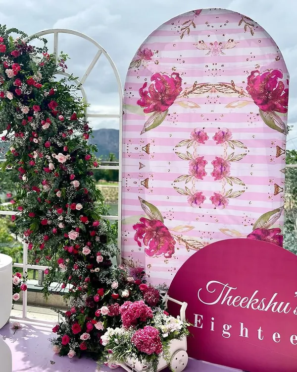 An absolutely dreamy 18th birthday setup on a balcony with a stunning view. We used a soft pink and magenta palette, a custom floral-print backdrop, and a lush, cascading flower arrangement to create a picture-perfect photo corner.