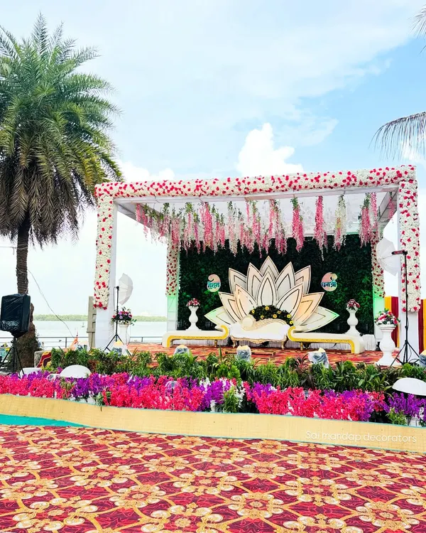 This is a beautiful outdoor engagement stage I created with a lotus theme. This setup by the water in Navi Mumbai includes a custom lotus backdrop, a lush green wall, and hanging floral arrangements, perfect for a memorable ring ceremony.