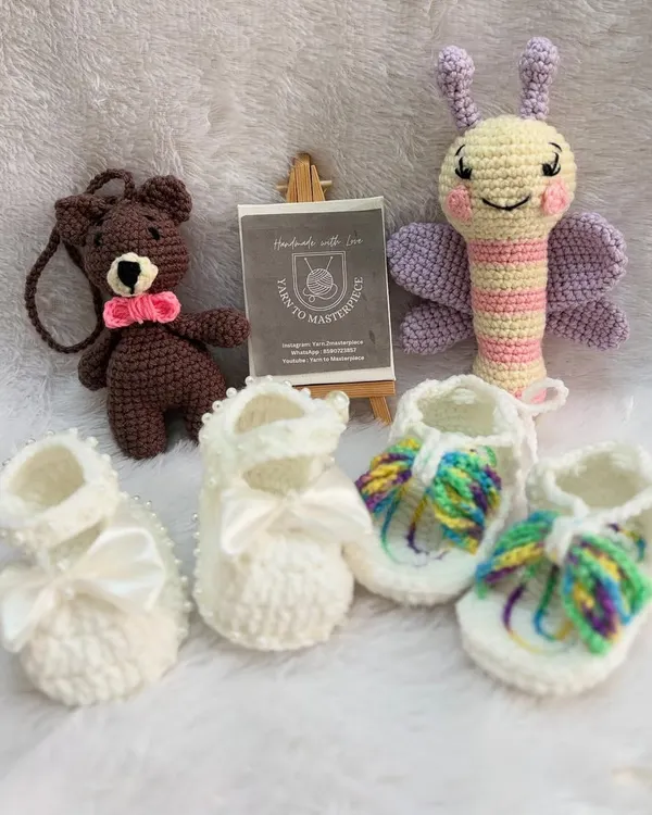 This custom gift hamper is full of variety, featuring two pairs of booties, a butterfly rattle, and a small bear keychain, offering a wonderful collection of handmade treasures.