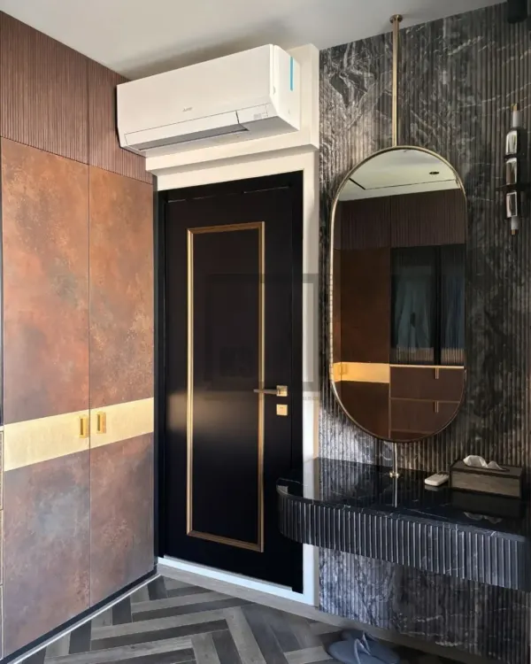This is a complete view of a modern luxury wardrobe and vanity. The design integrates a fluted black vanity table against a marble-patterned wall, complemented by earthy-toned wardrobe panels and a black door with gold trim.