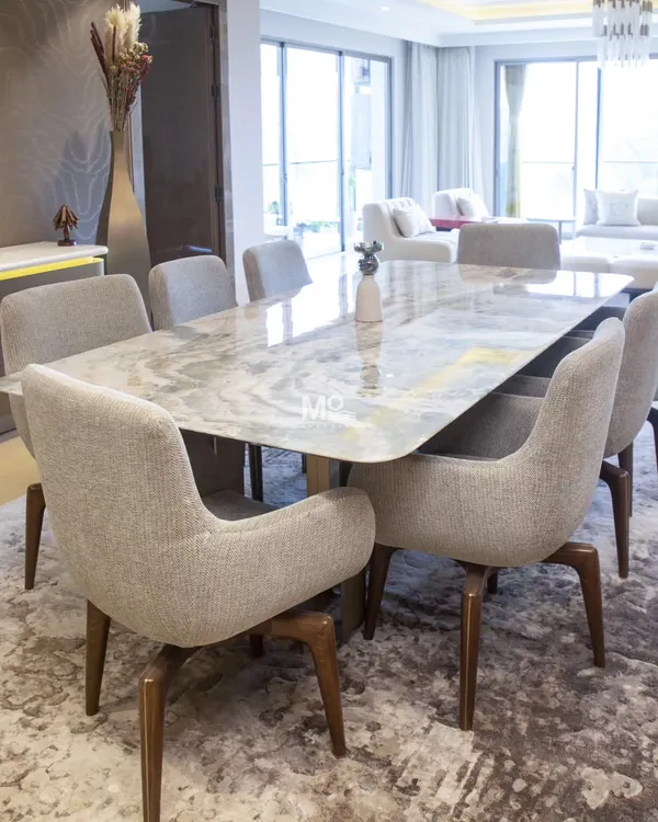 The Elysian Marble Dining Table and Sora Dining Chairs in a Suncity residence. The table's natural stone top and the chairs' sculpted backs create a setting of soft modernity and tactile richness.