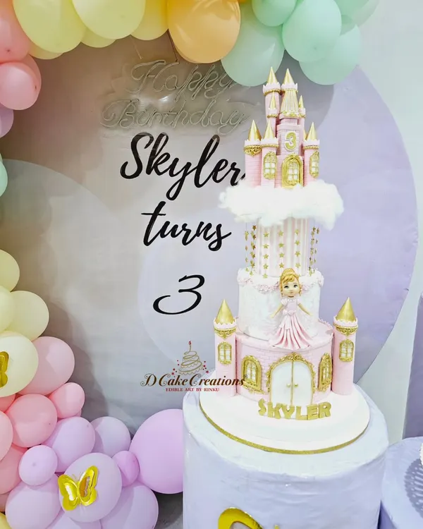 A magical princess castle cake for Skyler's 3rd birthday party. The towering pink and gold creation stands as the centerpiece of the celebration, surrounded by pastel balloons.