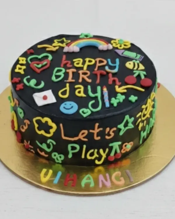 A fun and colorful doodle cake for Vihangi's birthday. This eggless chocolate cake is covered in black frosting and decorated with vibrant, hand-piped doodles, just like a chalkboard.