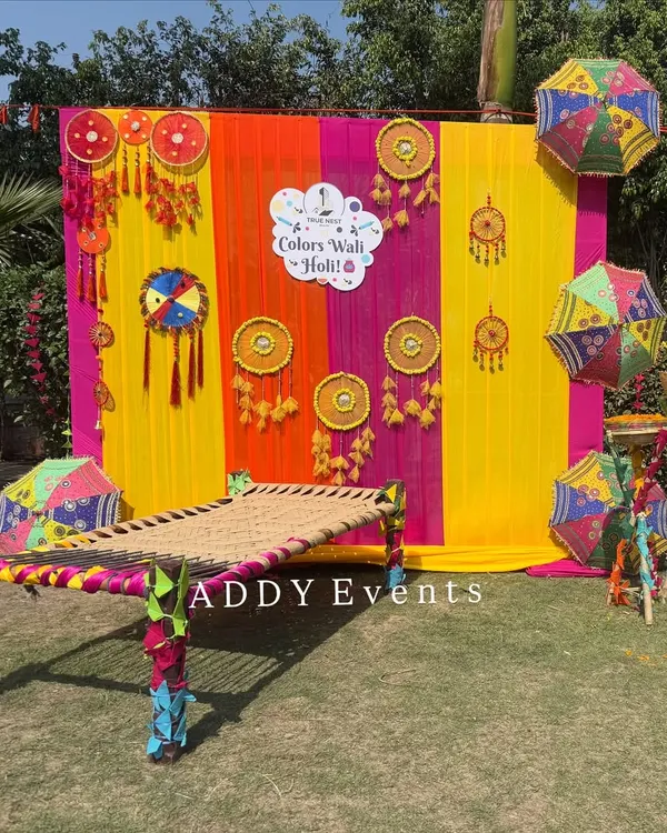 For a "Colors Wali Holi" party, we created this fun and traditional photo booth. It features a colorful draped backdrop, a decorated charpai (traditional woven cot), and festive hangings like dreamcatchers and umbrellas.