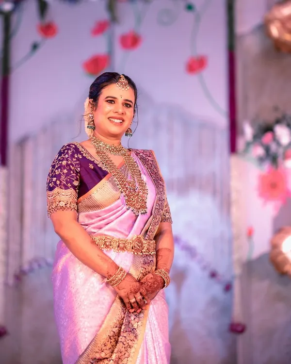 For her son's naming ceremony, I designed this rich purple blouse to contrast with her light lavender silk saree. The blouse is heavily embroidered with gold threadwork, creating a luxurious and celebratory look.