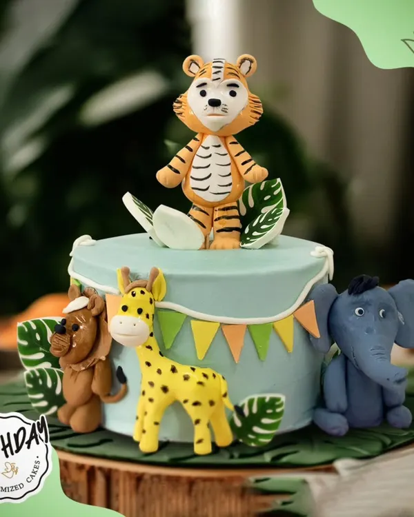 A delightful jungle-themed cake featuring a friendly tiger, giraffe, lion, and elephant. The cute, stylized animals make this a perfect choice for a young child's birthday.