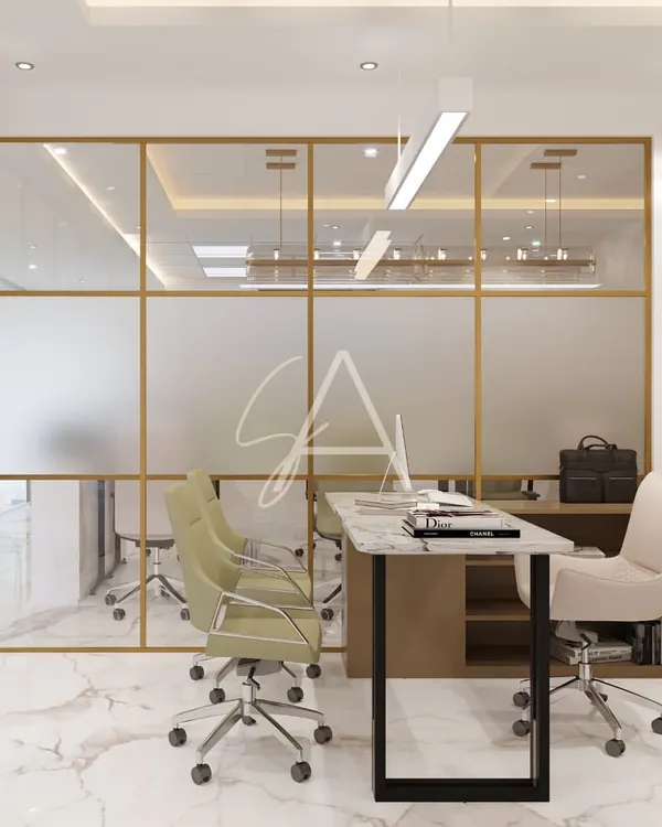 This office cabin features floor-to-ceiling glass partitions with a frosted lower half, balancing transparency and privacy. The gold-finished frames and marble flooring create a look of modern luxury, while the layout remains open and collaborative.