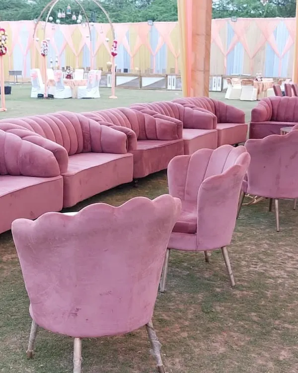 I offer modern furniture rentals to elevate your event's look. This image shows a collection of stylish pink velvet sofas and scalloped chairs arranged for an outdoor lounge area, adding a touch of modern elegance.