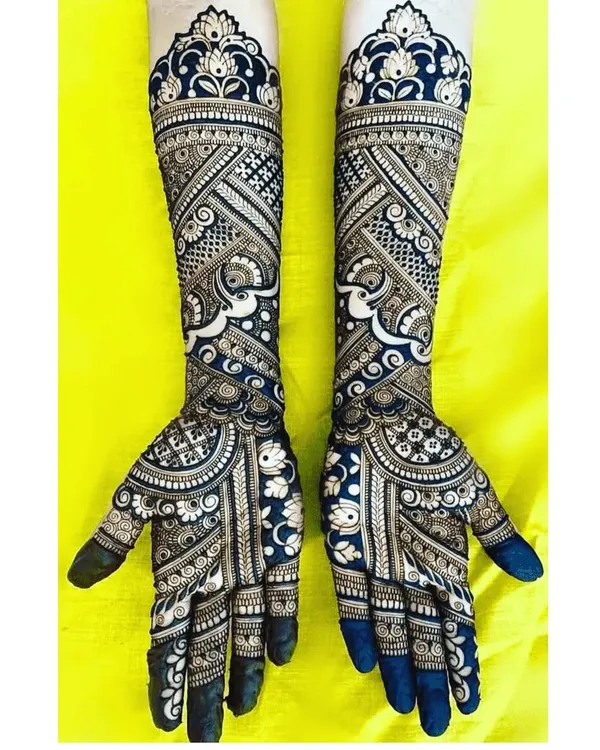 This is a perfect example of a negative space design, where the dark henna makes the skin's floral patterns pop. The bold, dark fingertips complete this modern and striking bridal look.