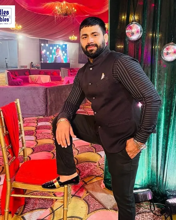 Our client looking sharp at a wedding reception in a custom-made black Bandhgala suit. The striped detailing on the sleeves adds a modern touch to the classic silhouette, making it a versatile choice for any formal celebration.