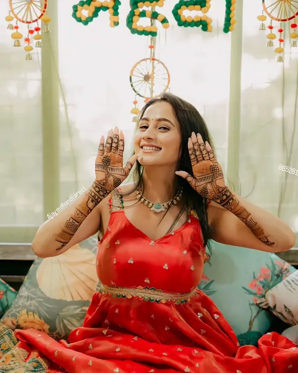 A happy client at her mehndi ceremony, smiling and showing her beautiful henna designs.