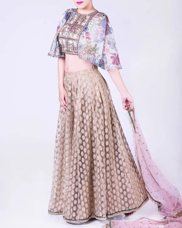 Blessed to create such memorable outfits. This ensemble features a floral organza cape crop top with detailed embroidery and a gold brocade skirt. The sheer cape adds a touch of modern drama to the traditional lehenga silhouette.