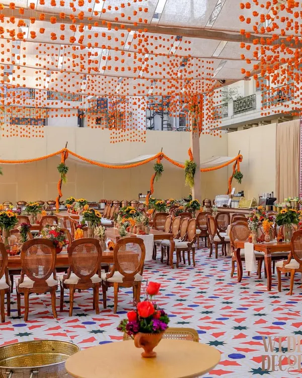 A wide view of the 'Old Delhi' themed brunch, showing the custom flooring, tenting with marigold garlands, and long community-style dining tables. The entire space was designed to feel like an open-air courtyard in a traditional haveli.