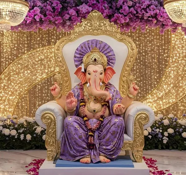 A truly regal setup for Ganesh Chaturthi, featuring the idol on an ornate throne. The backdrop is a curtain of golden lights, framed by columns of purple orchids and magnificent crystal chandeliers, creating a divine and luxurious atmosphere.