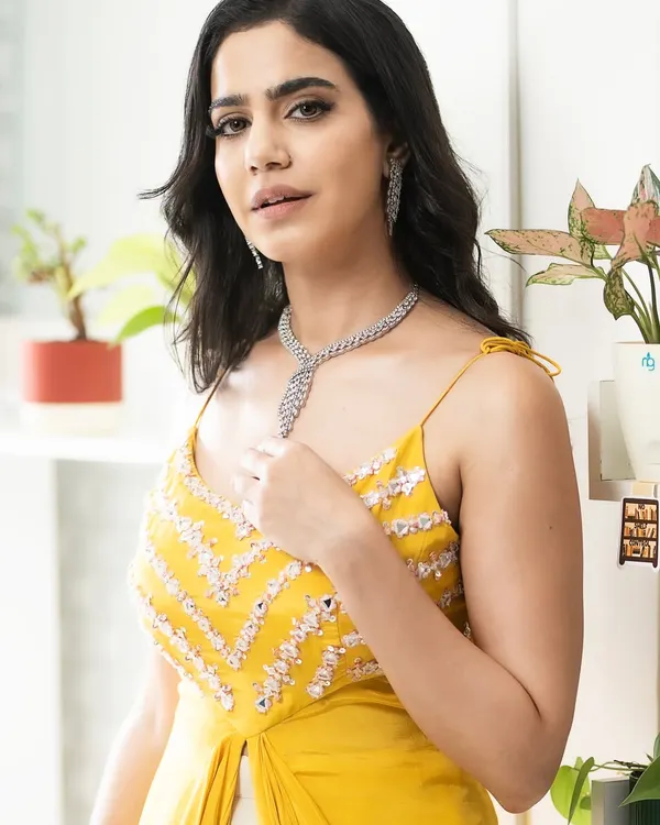 A close-up of the bright yellow Indo-Western outfit, focusing on the detailed embroidery on the bodice and the elegant diamond necklace.