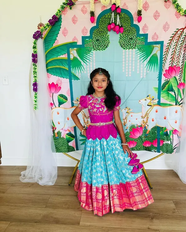 Our lovely client posing in her custom Banarasi pattu lehenga. The vibrant combination of a magenta peplum top and a turquoise brocade skirt looks stunning against the festive backdrop.