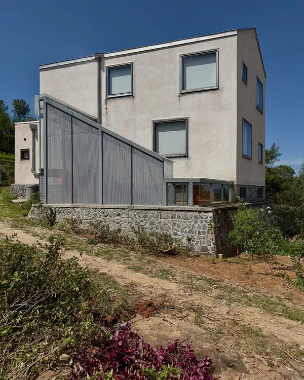 The 'Wildgrass' home in Coonoor, showing an addition with a perforated metal screen. We believe a home can grow like a city, and this project was a chance to intimately re-engage with the original structure and the settling landscape.